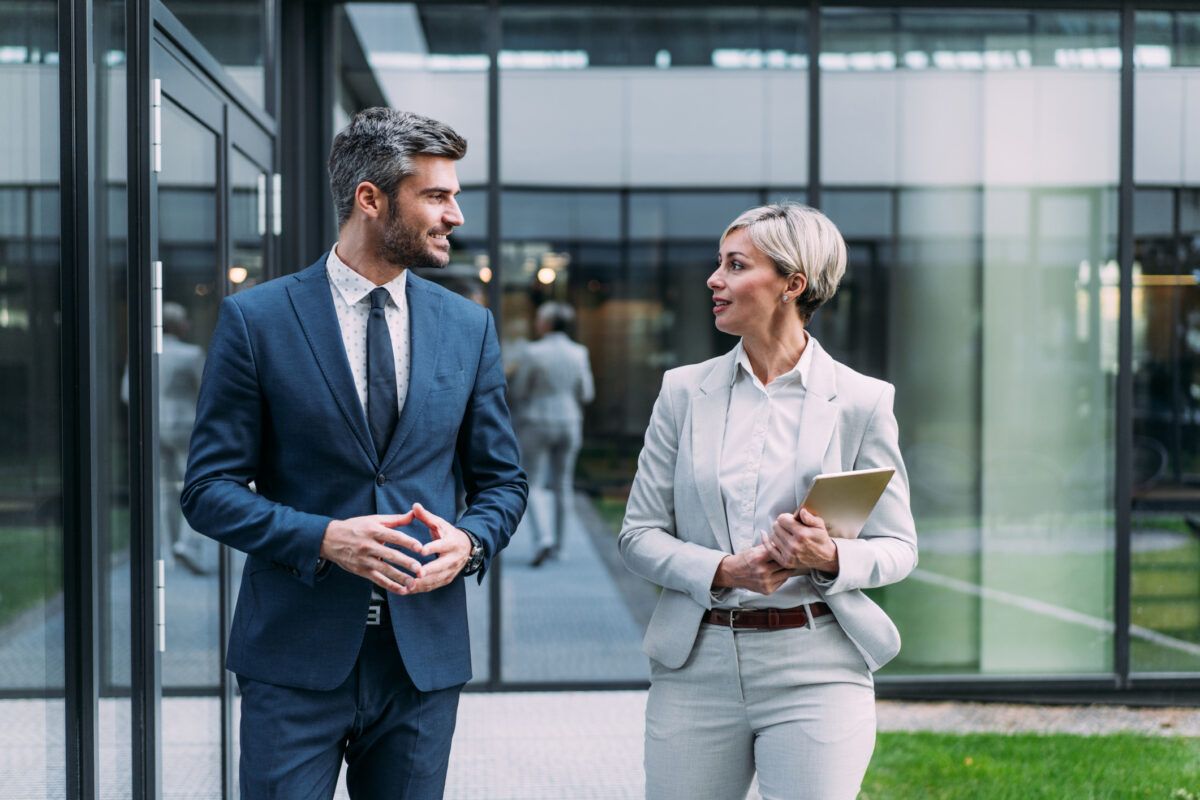 Business leaders walking and talking outside a glass office