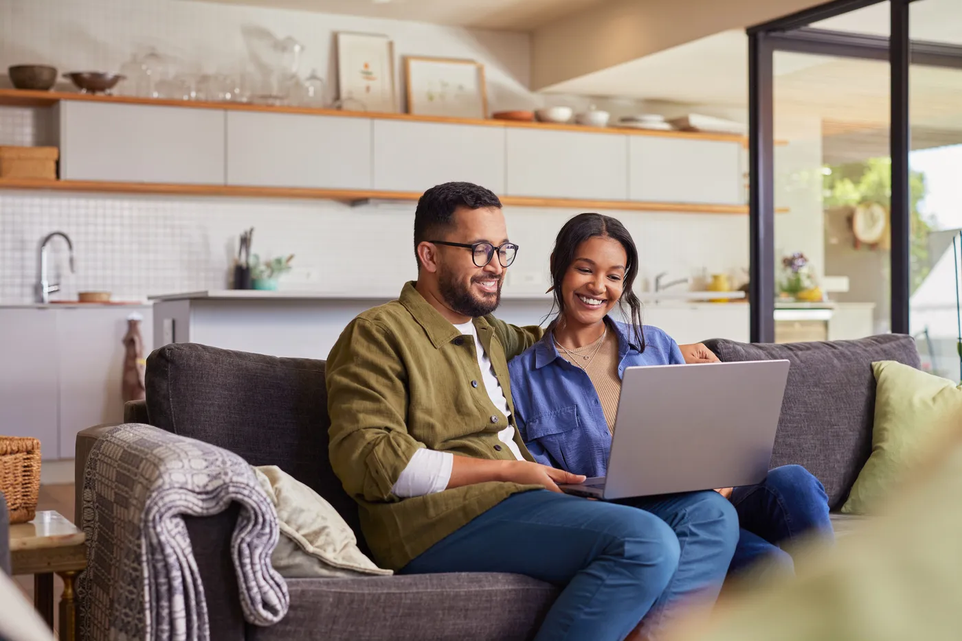 A smiling couple shopping online together on a laptop at home