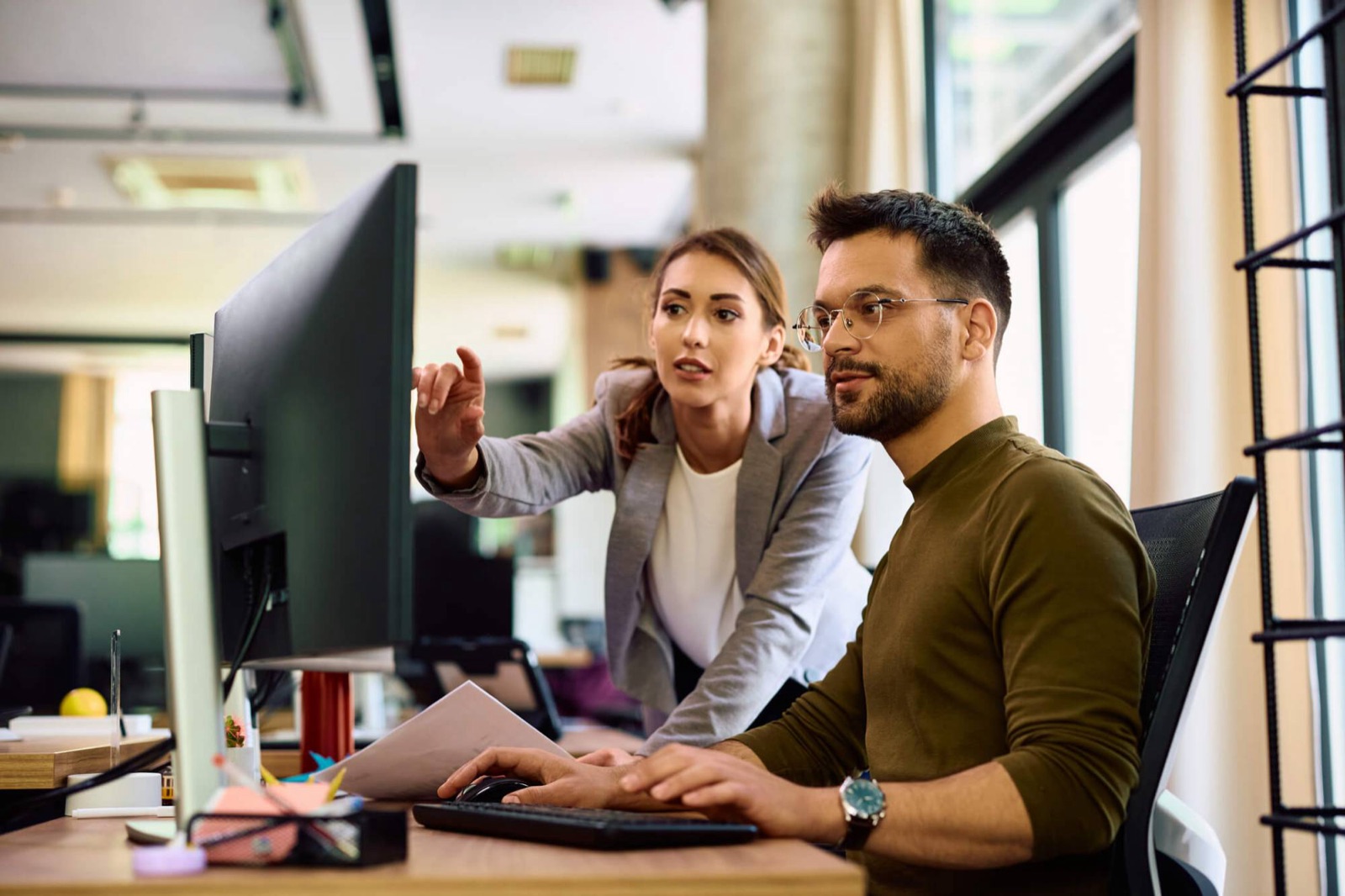 A developer and a colleague reviewing work together at a screen