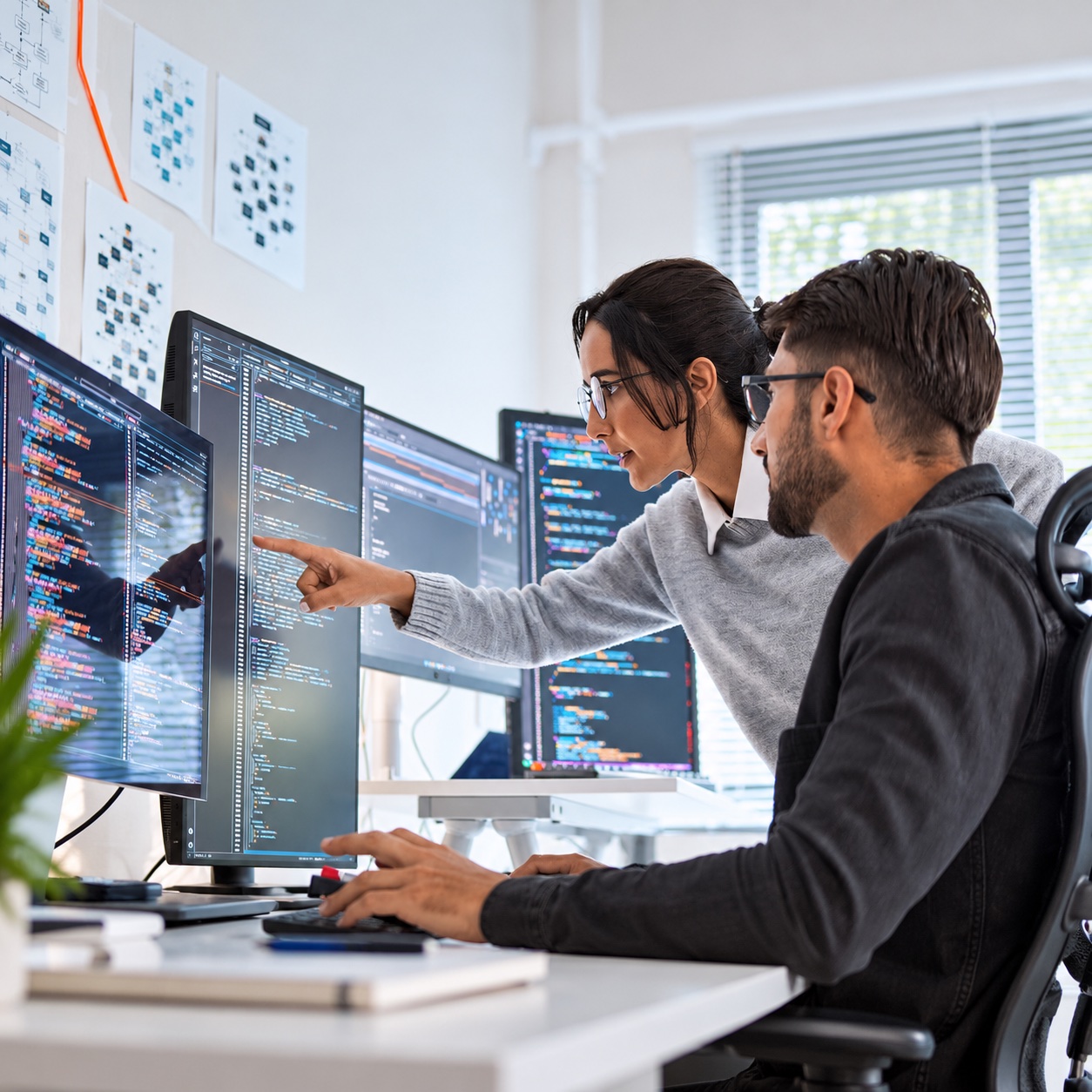 Two developers reviewing code together on several screens