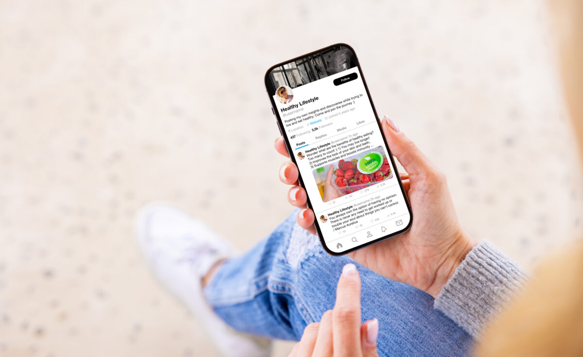 A person holding their phone scrolling through a LinkedIn profile page.